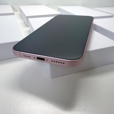 Smartphone rosa com ecrã preto sobre caixas brancas num fundo branco.