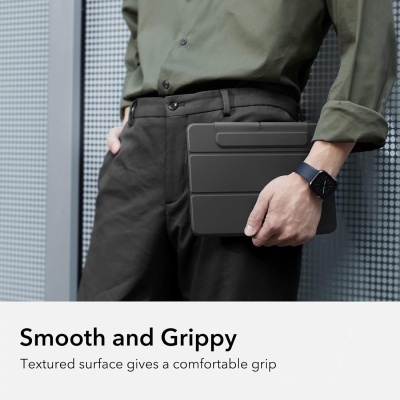 Pessoa segurando tablet com capa preta texturada junto a parede cinza