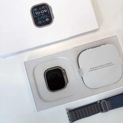 Apple Watch preto na embalagem branca com bracelete cinzenta azulada.