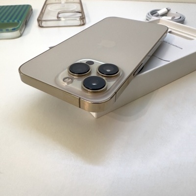 Smartphone com capa transparente e três lentes traseiras sobre caixa branca com acessórios