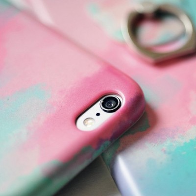 Capa de telemóvel colorida com padrão marmoreado e anel metálico em forma de coração ao fundo