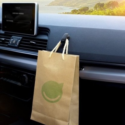 Saco de papel castanho com alças pendurado no interior de um carro