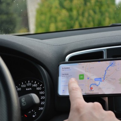 Interior de carro com volante, painel e smartphone a mostrar mapa e rota