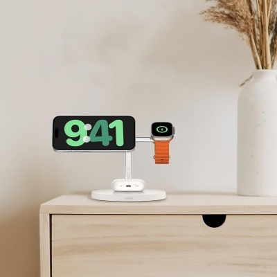 Base de carregamento Belkin com smartphone e smartwatch em cima de móvel de madeira clara e vaso branco