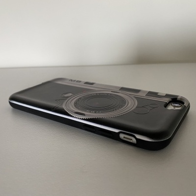 Capa preta para smartphone com desenho de lente de máquina fotográfica.