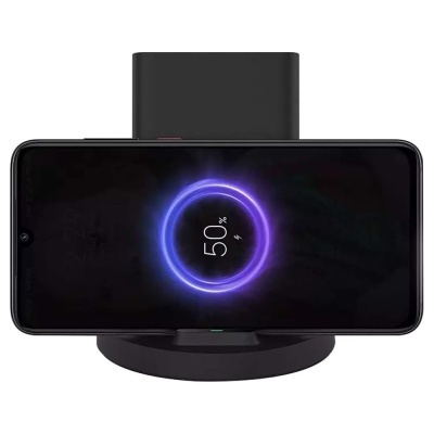 Smartphone preto a carregar sem fios num carregador preto, indicador de 50% no ecrã.