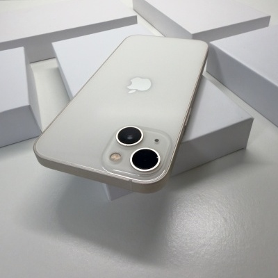 Smartphone branco Apple iPhone com duas câmaras traseiras em superfície branca e caixas brancas ao fundo