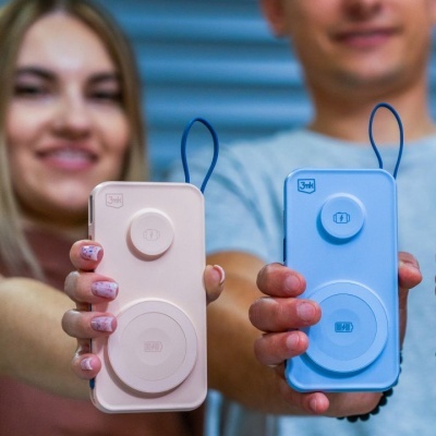 Dois smartphones com capas de carregamento em rosa e azul segurados por duas pessoas