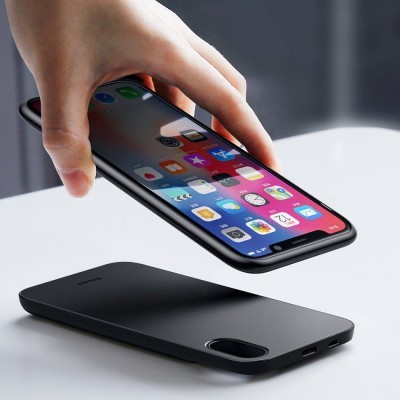 Smartphone colorido a ser colocado num carregador sem fios preto sobre mesa branca