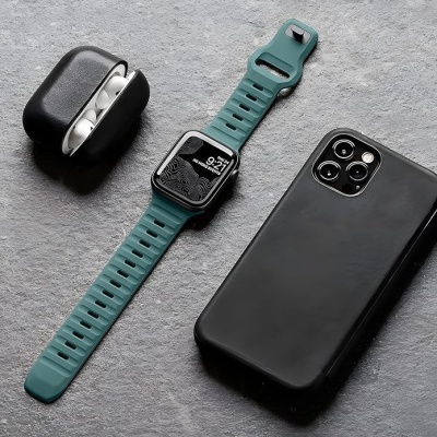 Relógio inteligente verde, auscultadores brancos em estojo preto aberto, telemóvel preto com capa preta sobre superfície cinzenta