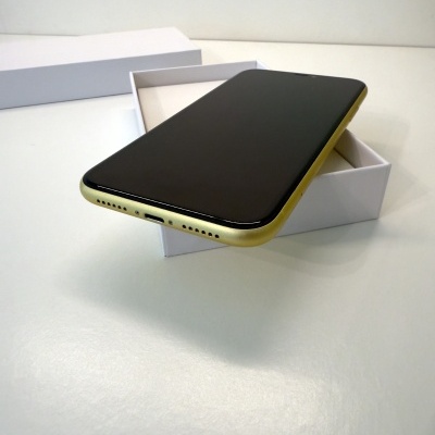 Smartphone preto com bordas douradas sobre caixa branca aberta