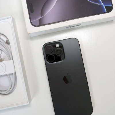 Smartphone Apple iPhone preto ao lado da caixa branca com imagem e texto iPhone e cabo USB.