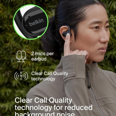 Pessoa a usar auricular intra-auricular preto da marca belkin junto a fundo de folhagem verde.