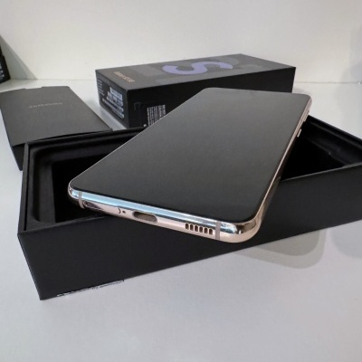 Smartphone com ecrã preto e bordas douradas em embalagem preta aberta