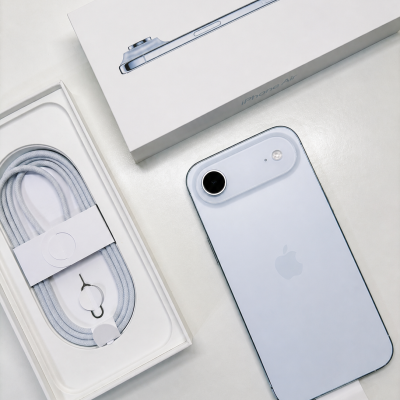 Smartphone cinzento claro ao lado da caixa iPhone Air e embalagem com cabo e ferramenta SIM