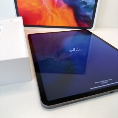 Tablet preto com ecrã ligado mostrando olá com caixa branca aberta ao lado