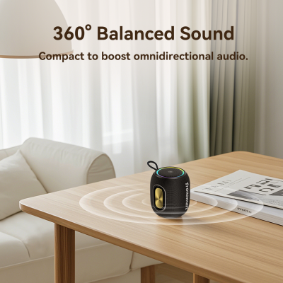 Coluna portátil preta detalhada dourada numa mesa de madeira clara