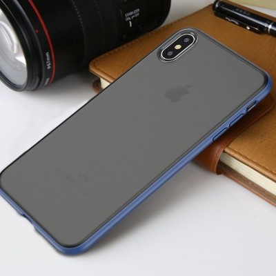 Smartphone Apple iPhone com capa azul sobre superfície branca, junto a lente de câmara preta e caderno castanho.