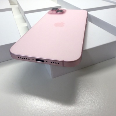 Smartphone cor-de-rosa com câmeras duplas sobre caixas brancas.