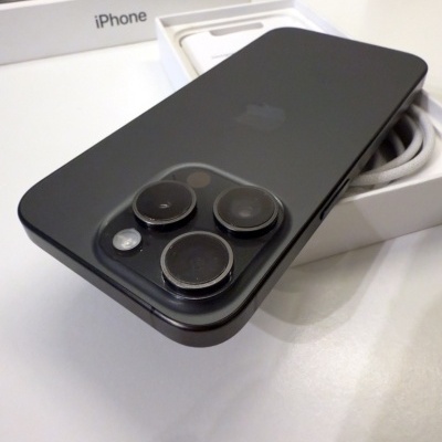 iPhone preto com três câmeras numa caixa branca com texto 'iPhone'.