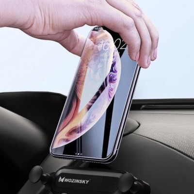 Suporte para telemóvel WOZINSKY preto num carro a segurar um telemóvel com ecrã iluminado.