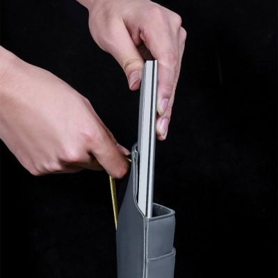 Capa cinza com portátil prateado sendo colocado por mãos sobre fundo preto