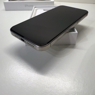 iPhone prateado com ecrã preto em cima da caixa branca com texto iPhone