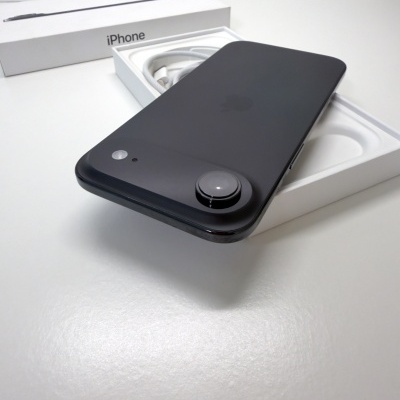 Smartphone iPhone preto brilhante sobre caixa branca com cabo.