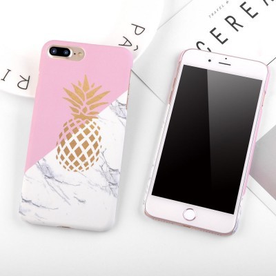 Capa de smartphone rosa e mármore com abacaxi dourado ao lado de telemóvel branco com ecrã apagado