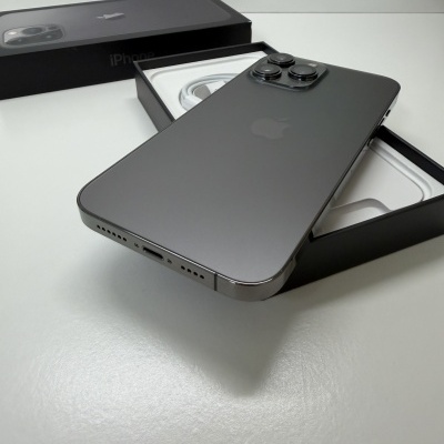 Smartphone iPhone cinza espacial em cima da caixa preta aberta sobre superfície branca.