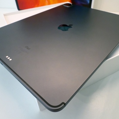 Tablet iPad cinza escuro metálico com logótipo Apple e embalagem branca ao fundo