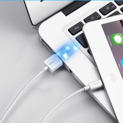 Cabo USB branco UGREEN ligado a portátil e tablet com efeitos de luz azul.
