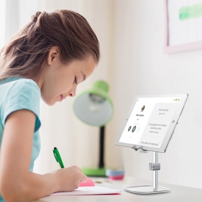 Menina a estudar numa secretária com tablet num suporte metálico