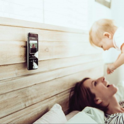Smartphone fixado numa cabeceira de madeira com mulher e bebé ao lado