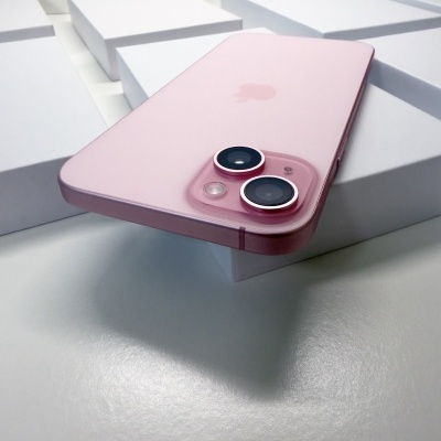 Smartphone cor-de-rosa com duas câmeras grandes apoiado em caixas brancas.