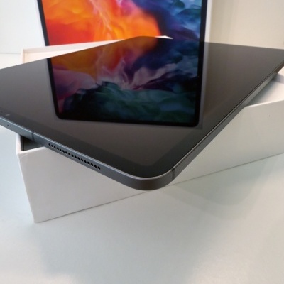 Tablet preto sobre caixa branca com ecrã colorido refletido