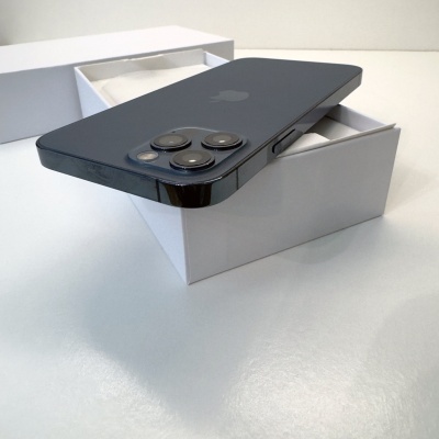 Smartphone preto com três câmaras traseiras sobre caixa branca aberta