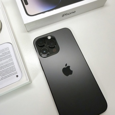 Smartphone iPhone preto junto a caixas brancas e manual, em superfície branca