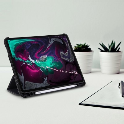 Tablet preto com capa protetora e caneta digital branca numa mesa com caderno, caneta e plantas