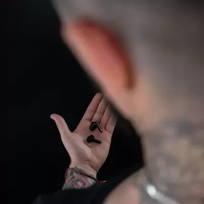 Mão masculina segurando auriculares sem fios pretos