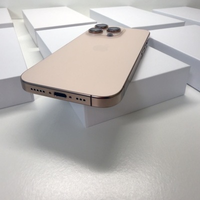 Smartphone dourado com três câmeras traseiras em caixas brancas