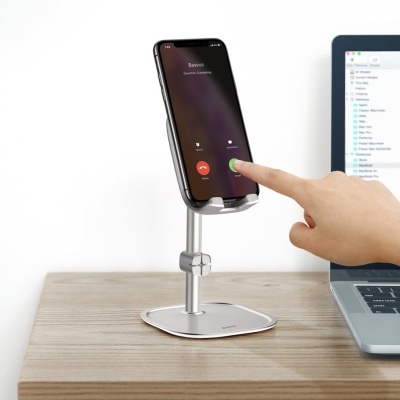 Suporte em metal para telemóvel com smartphone ligado sobre mesa de madeira junto a computador portátil