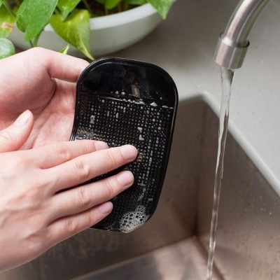 Escova de cabelo preta a ser lavada debaixo de uma torneira