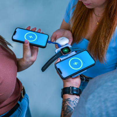 Três pessoas seguram smartphones a carregar, um relógio inteligente e auscultadores sem fios.