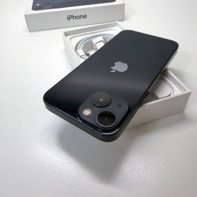 Smartphone iPhone preto com duas câmaras traseiras junto a caixa branca com cabo USB