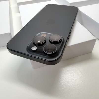 Smartphone preto Apple com três câmaras grandes na parte traseira sobre caixas brancas.