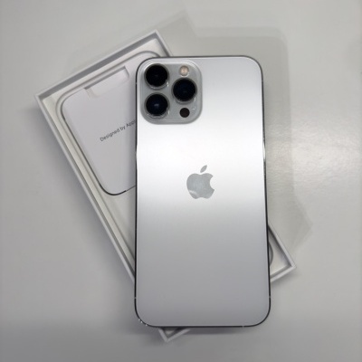 iPhone prateado com três câmeras sobre caixa branca com texto 'Designed by Apple'