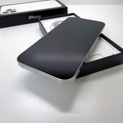 Smartphone iPhone preto sobre caixa preta aberta em superfície branca