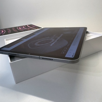 Tablet prateado com ecrã escuro na caixa branca aberta