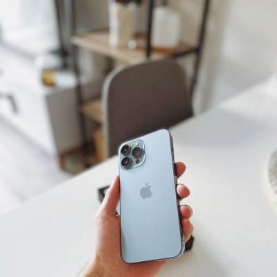 Pessoa segurando um iPhone azul claro com três câmaras na traseira